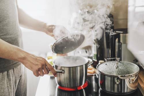 young man cooking fresh food home opening lid steaming pot 1 • الشهبندر